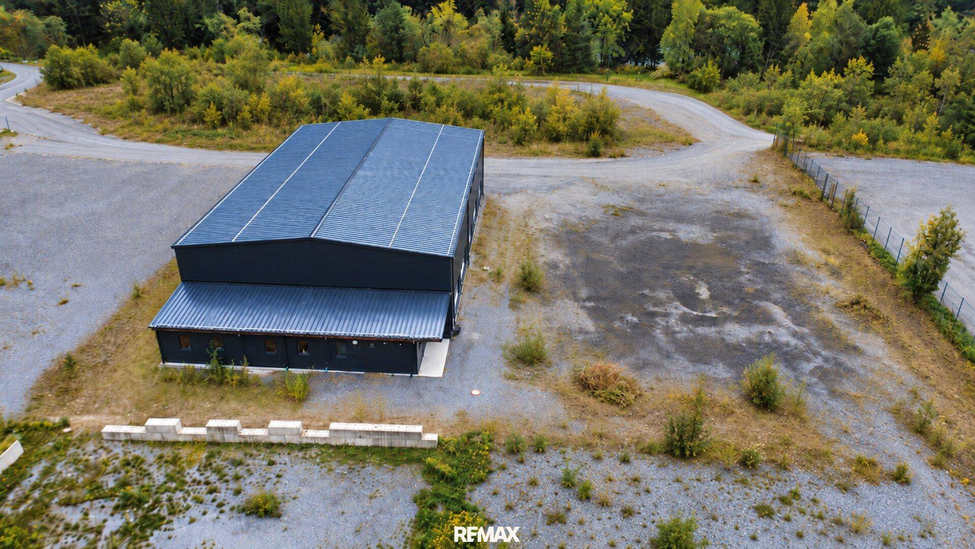 Luftaufnahme des Industriegebäudes mit angrenzendem Grundstück und Zufahrtswegen in ländlicher Umgebung.