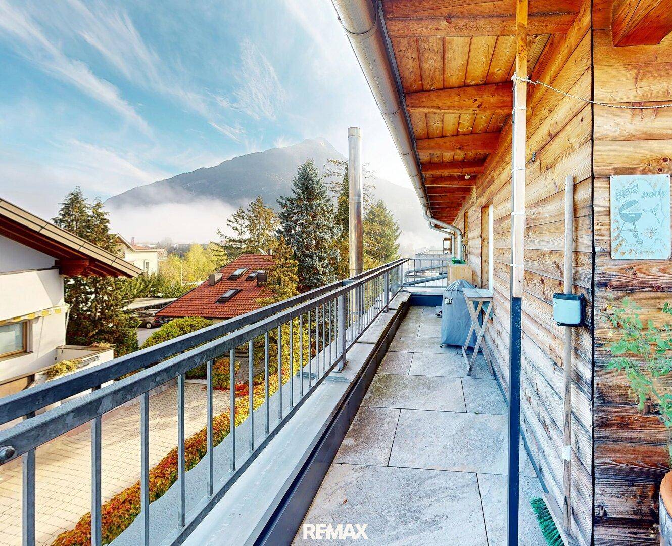 Langer Balkon mit Steinboden, Holzverkleidung und Bergblick, ideal für frische Luft.