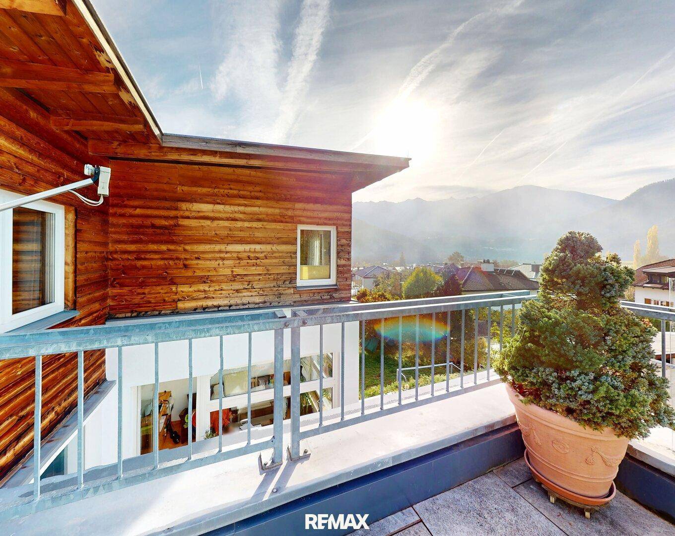 Sonniger Balkon mit Holzfassade und weitem Blick auf die umliegende Berglandschaft.