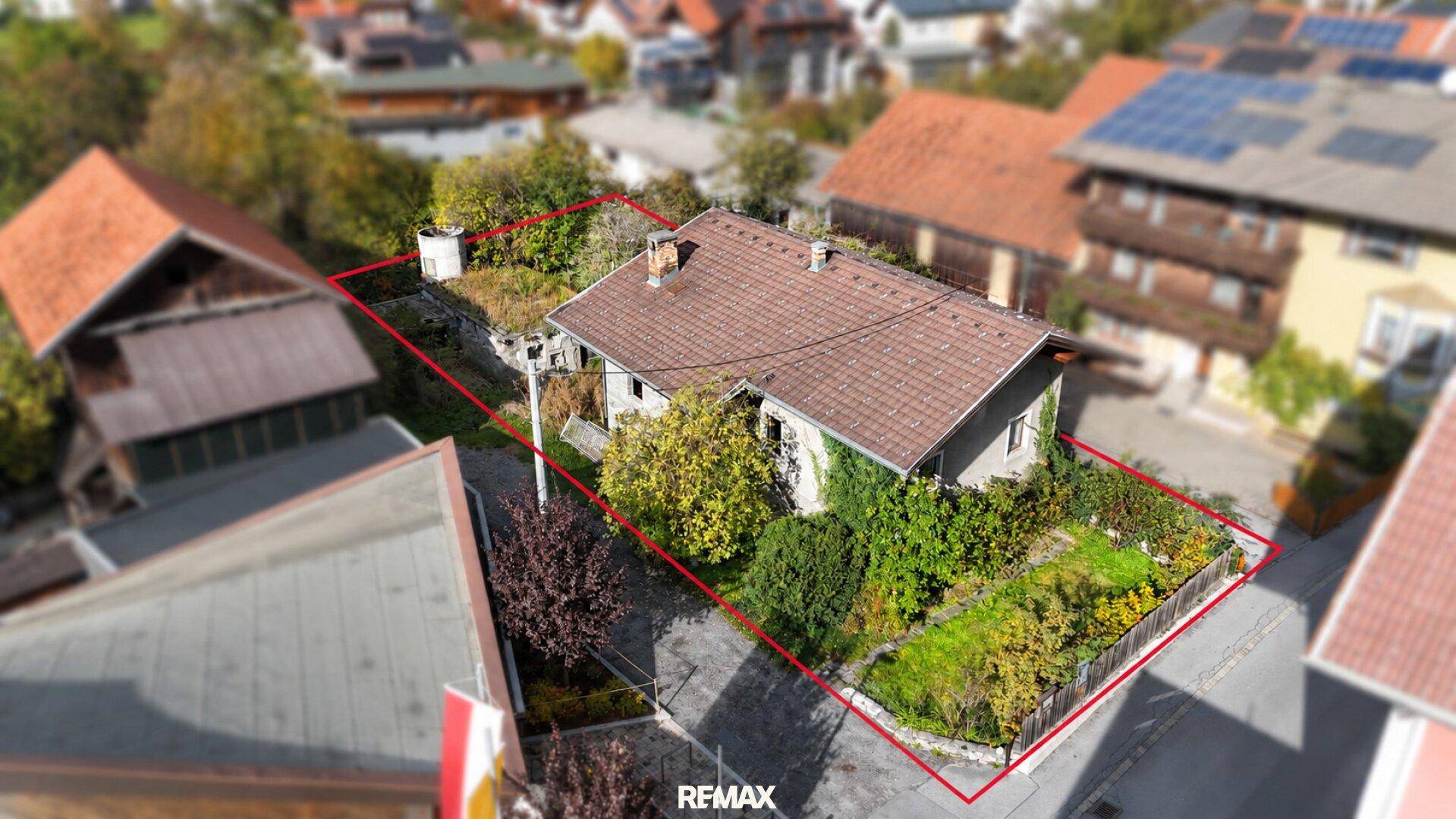 Luftaufnahme eines Hauses mit Grundstücksgrenzen, umgeben von Bäumen und anderen Gebäuden.