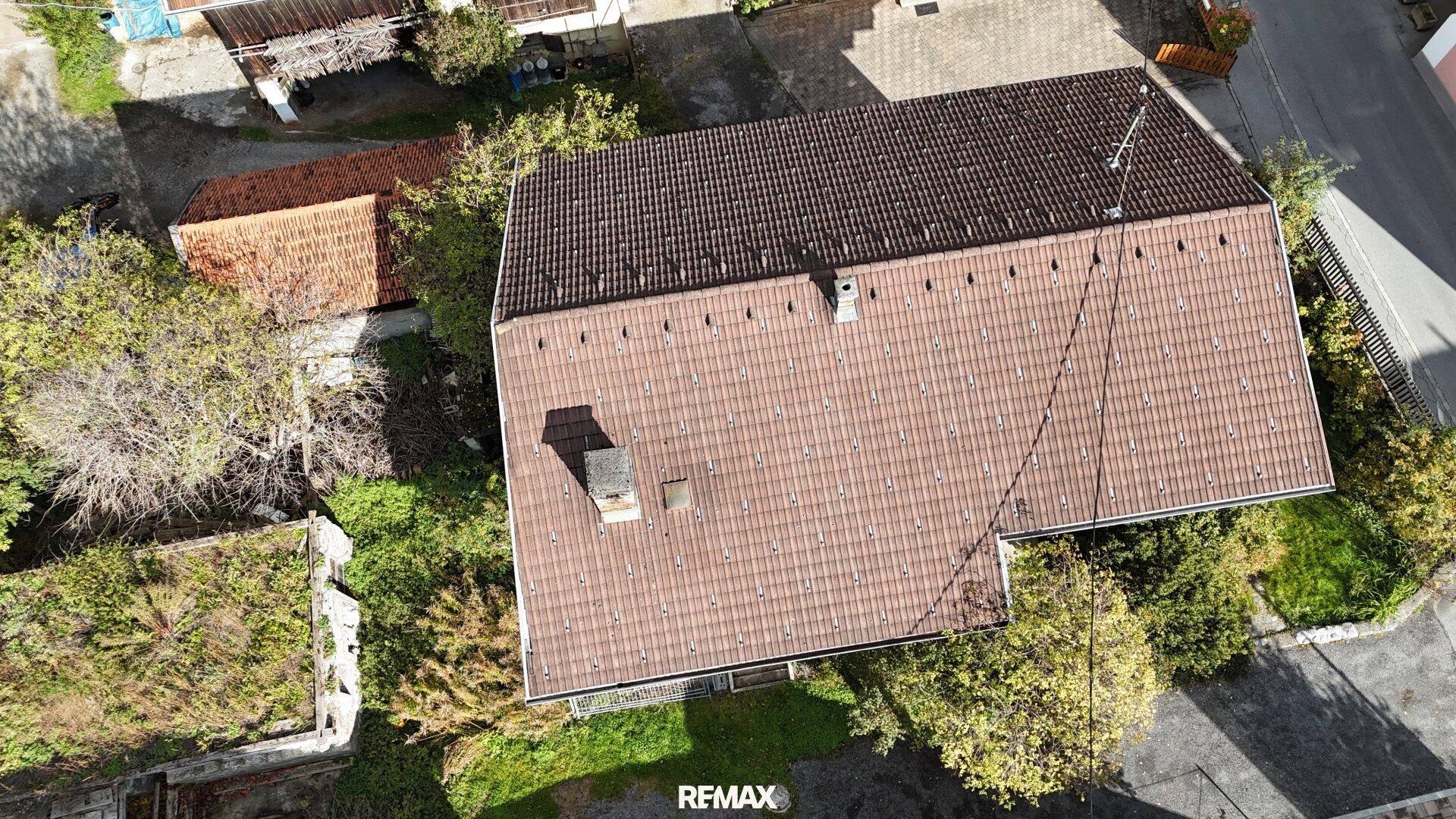 Direkte Draufsicht auf das Ziegeldach des Hauses und den umliegenden Gartenbereich.