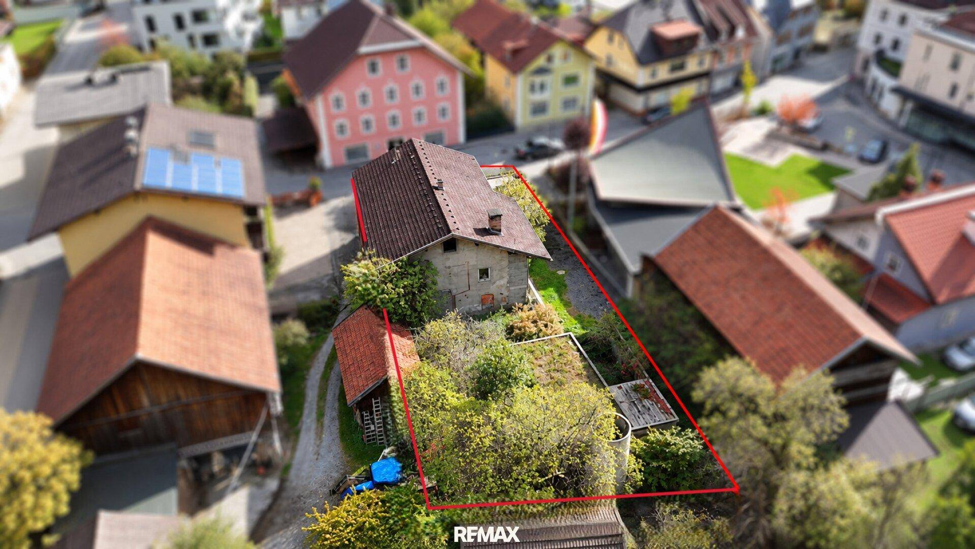 Luftaufnahme des Hauses mit markierten Grundstücksgrenzen, umgeben von Bäumen und ländlicher Bebauung.