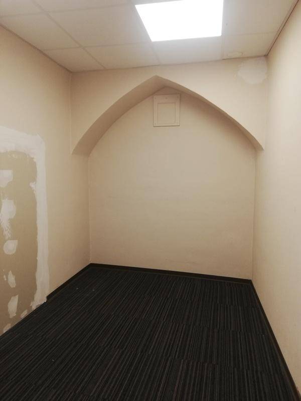 Kleiner, leerer Raum mit einer gewölbten Nische in der Wand und einem quadratischen Deckenlicht.
