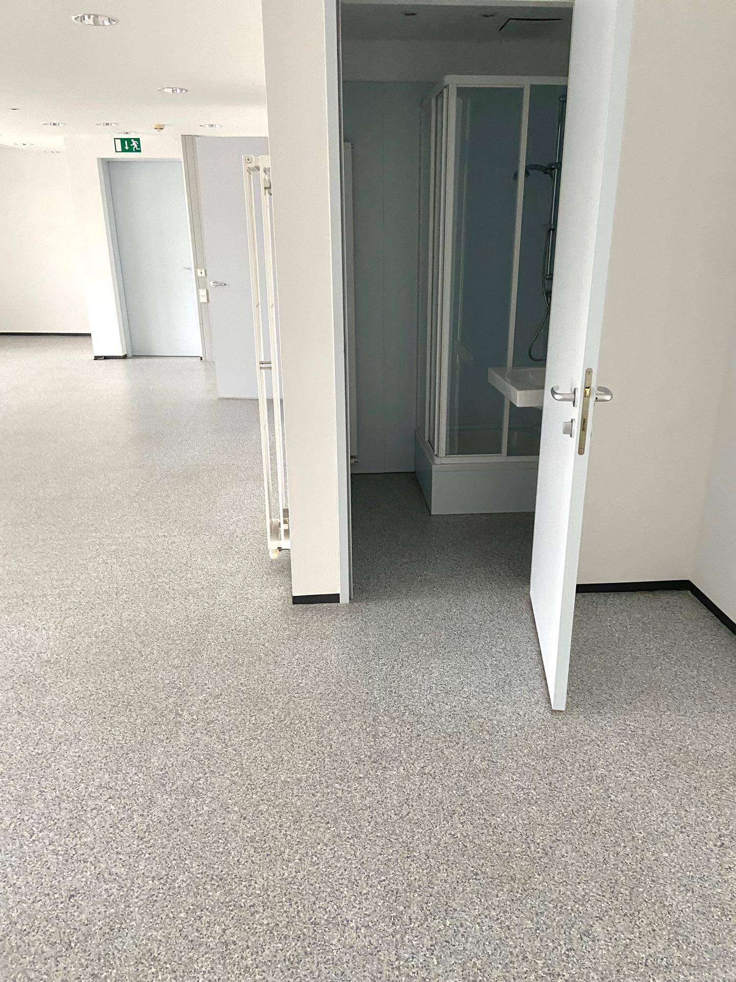Heller Flur mit mehreren Türen, der zu verschiedenen Räumen führt, inklusive einer Duschkabine.