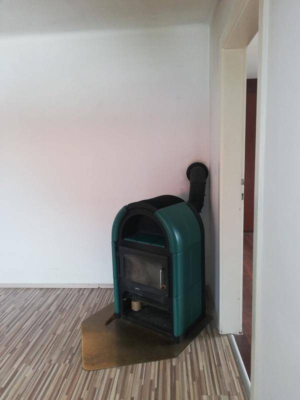 Nahaufnahme eines modernen, freistehenden Holzofens in einem Wohnraum mit Laminatboden.