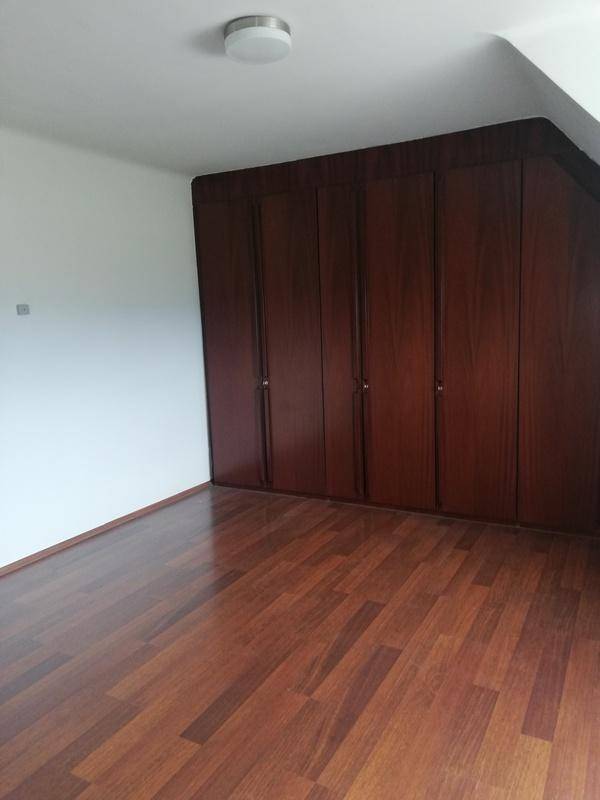 Schlafzimmer mit dunklem Holzboden, Dachschrägen und integrierten Einbauschränken.
