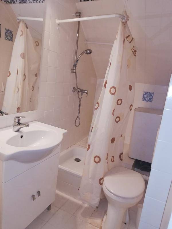 Badezimmer mit weiß gefliesten Wänden und Boden, ausgestattet mit Dusche, WC und Waschbecken.