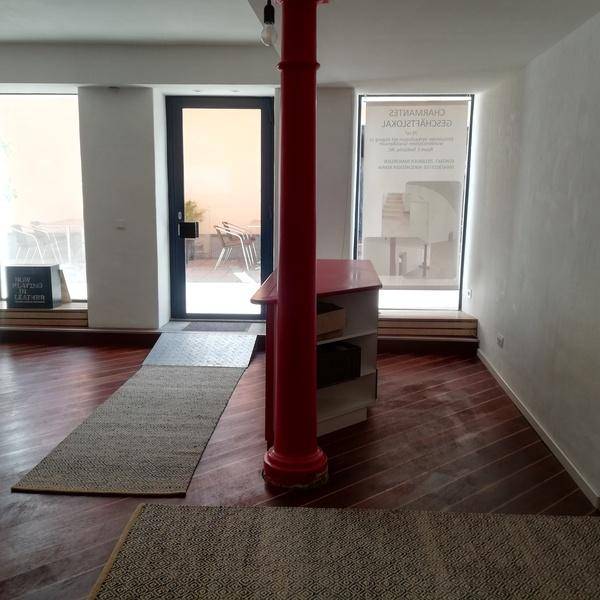 Innenansicht eines Geschäftsraums mit roter Säule, Theke und Zugang zu einem Außenbereich.