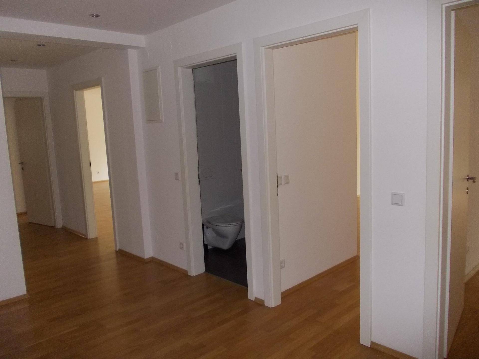 Heller Flur mit Parkettboden und Zugang zu verschiedenen Räumen, inklusive Gäste-WC.