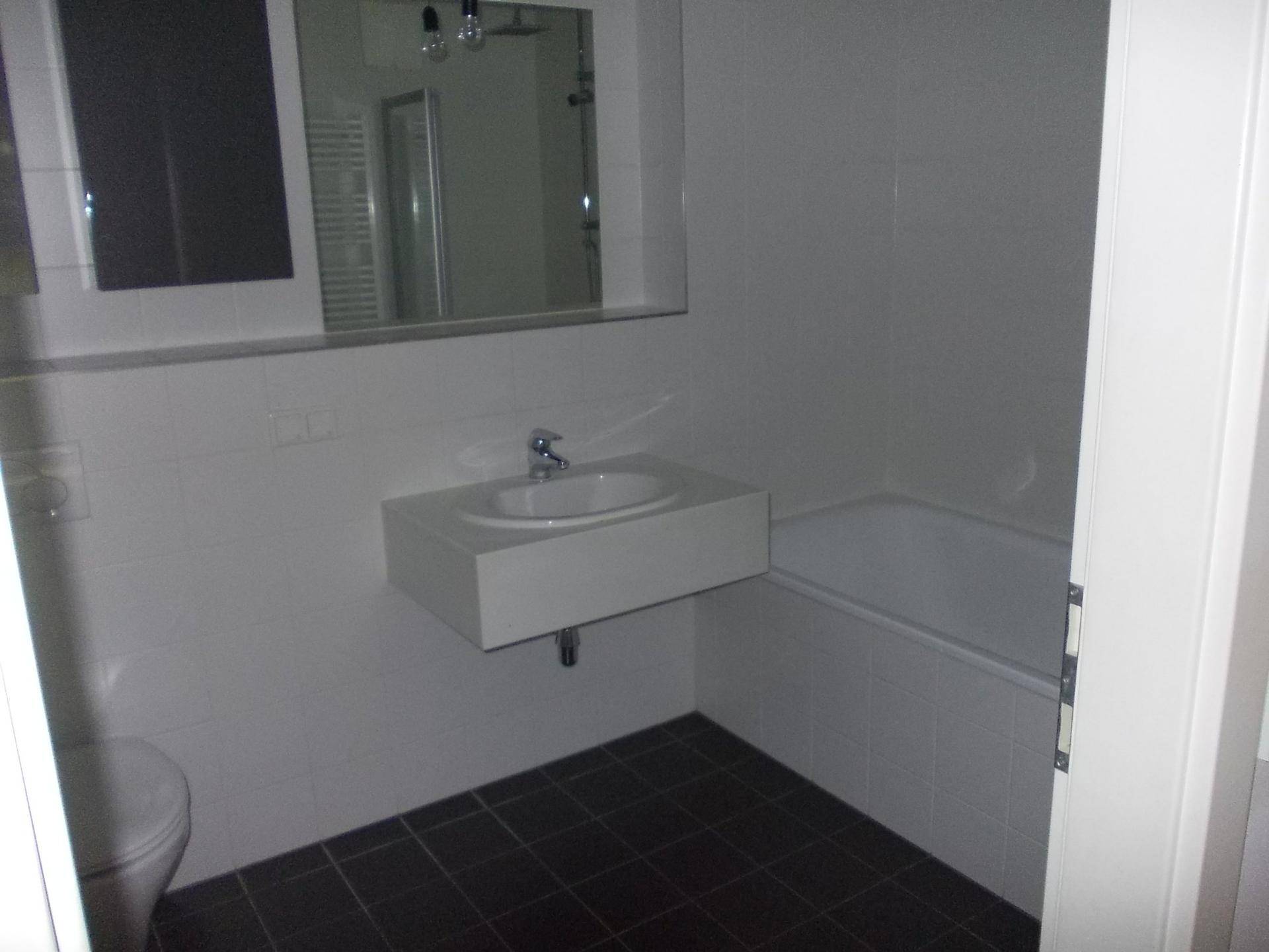 Modernes Badezimmer mit Badewanne, Waschbecken und Spiegel, ausgestattet mit weißen Fliesen.