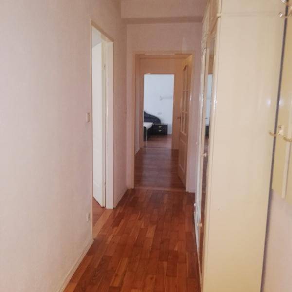 Langer Flur mit Holzparkettboden und Zugang zu verschiedenen Zimmern der Wohnung.
