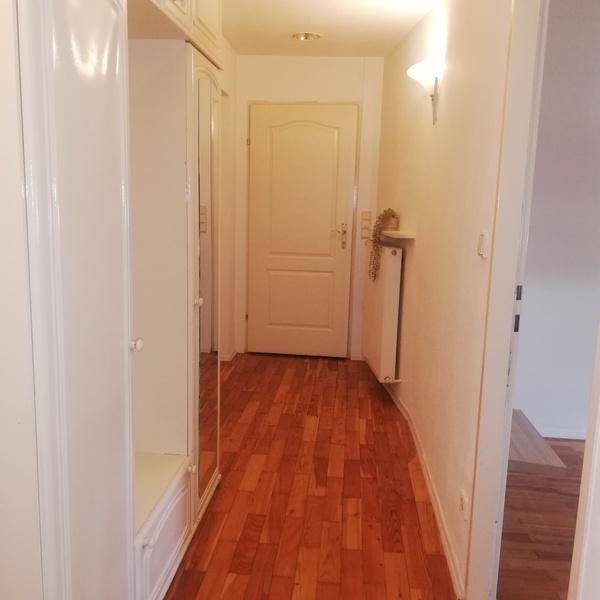 Heller Eingangsbereich mit Holzparkettboden und einem großen Spiegelschrank.
