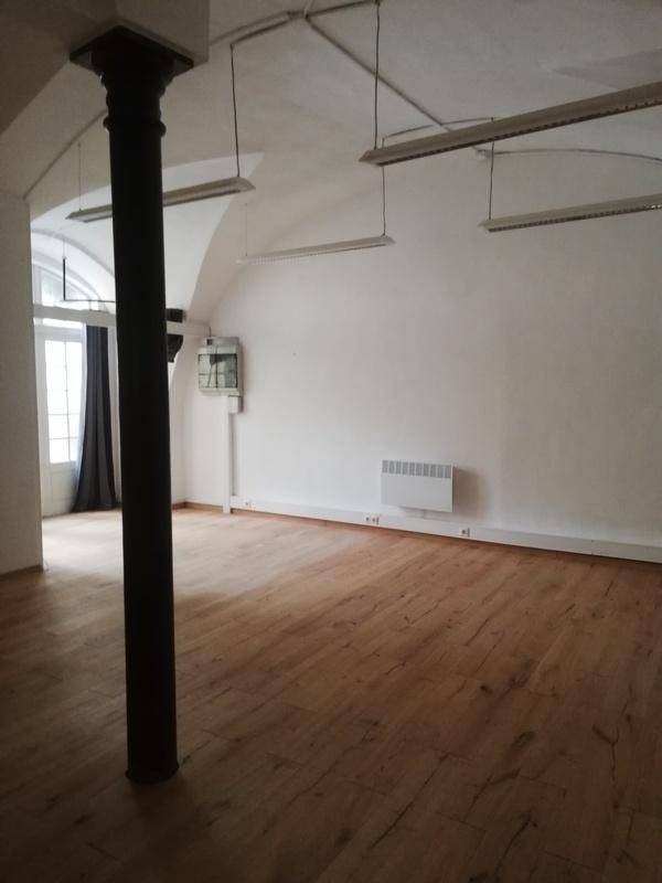 Geräumiger Raum mit Holzboden, gewölbter Decke und einem markanten schwarzen Pfeiler, mit natürlichem Lichteinfall.