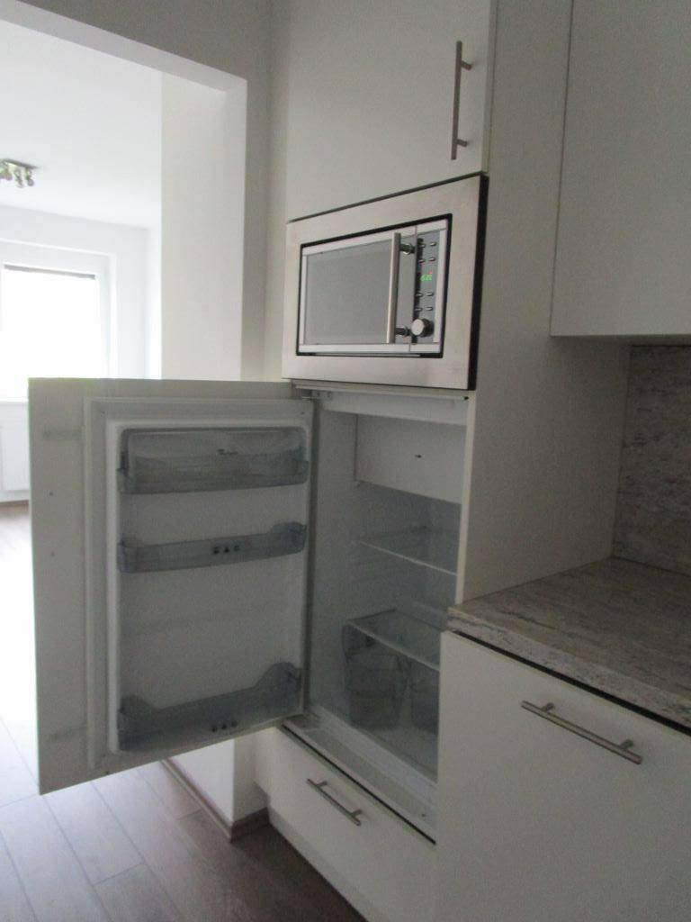Küchenzeile mit integriertem Kühlschrank und Mikrowelle über der Arbeitsplatte.
