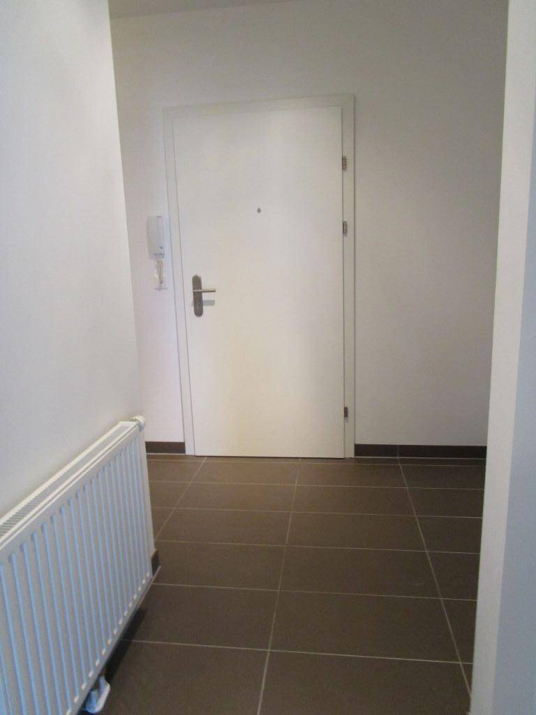 Eingangsbereich mit Fliesenboden, Heizkörper und weißer Wohnungstür.