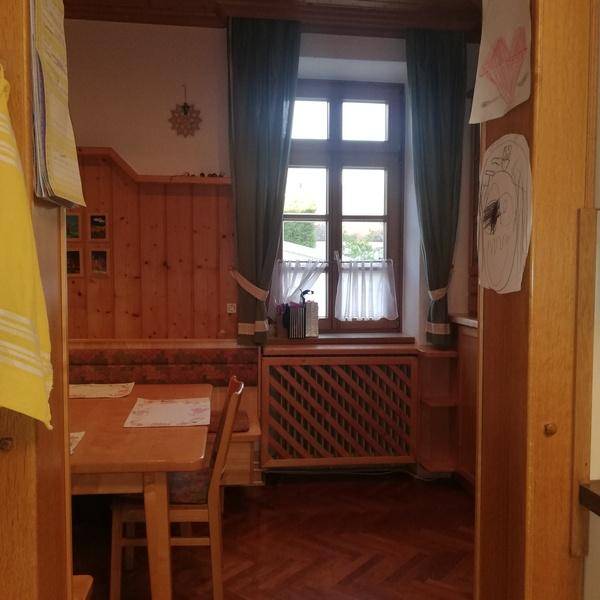Gemütlicher Essbereich mit Holztäfelung, Sitzbank und Blick durch das Fenster.