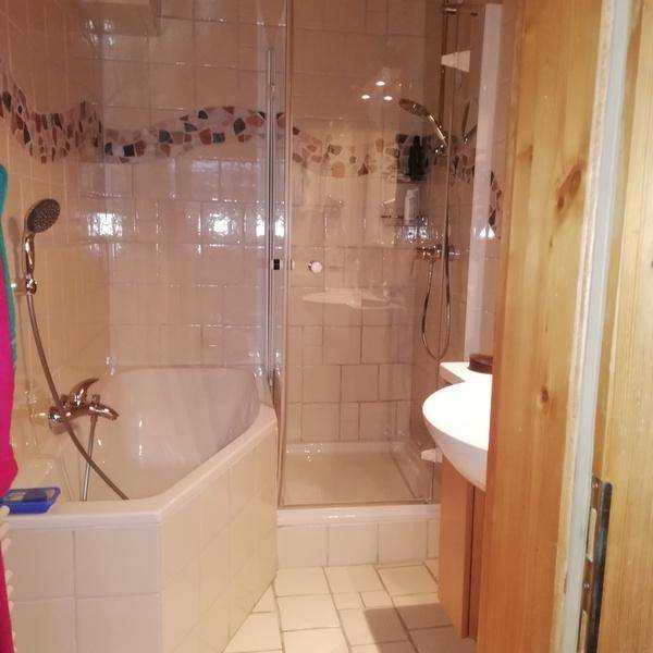 Badezimmer mit Badewanne, Duschkabine und Waschbecken, gefliest in hellen Tönen.