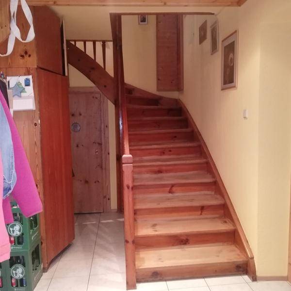 Treppenhaus mit Holztreppe und gelben Wänden, führt in die obere Etage.