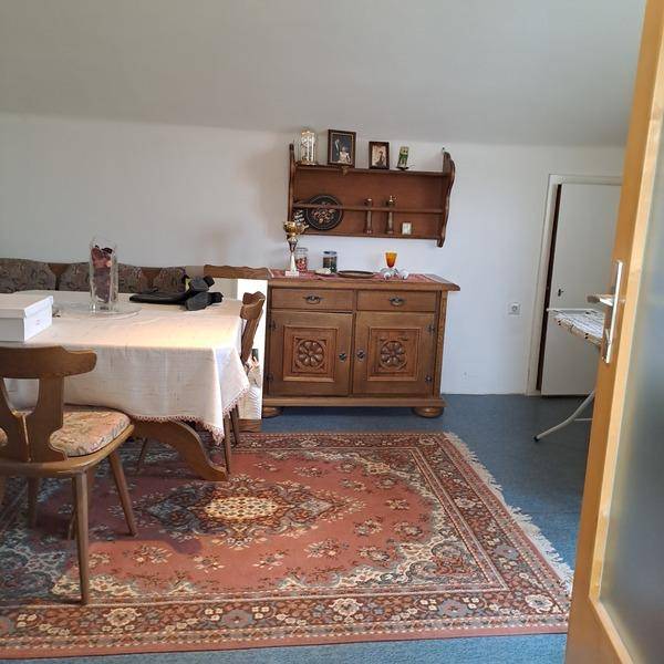 Esszimmer mit Teppichboden, Holztisch und traditionellem Sideboard an der Wand.