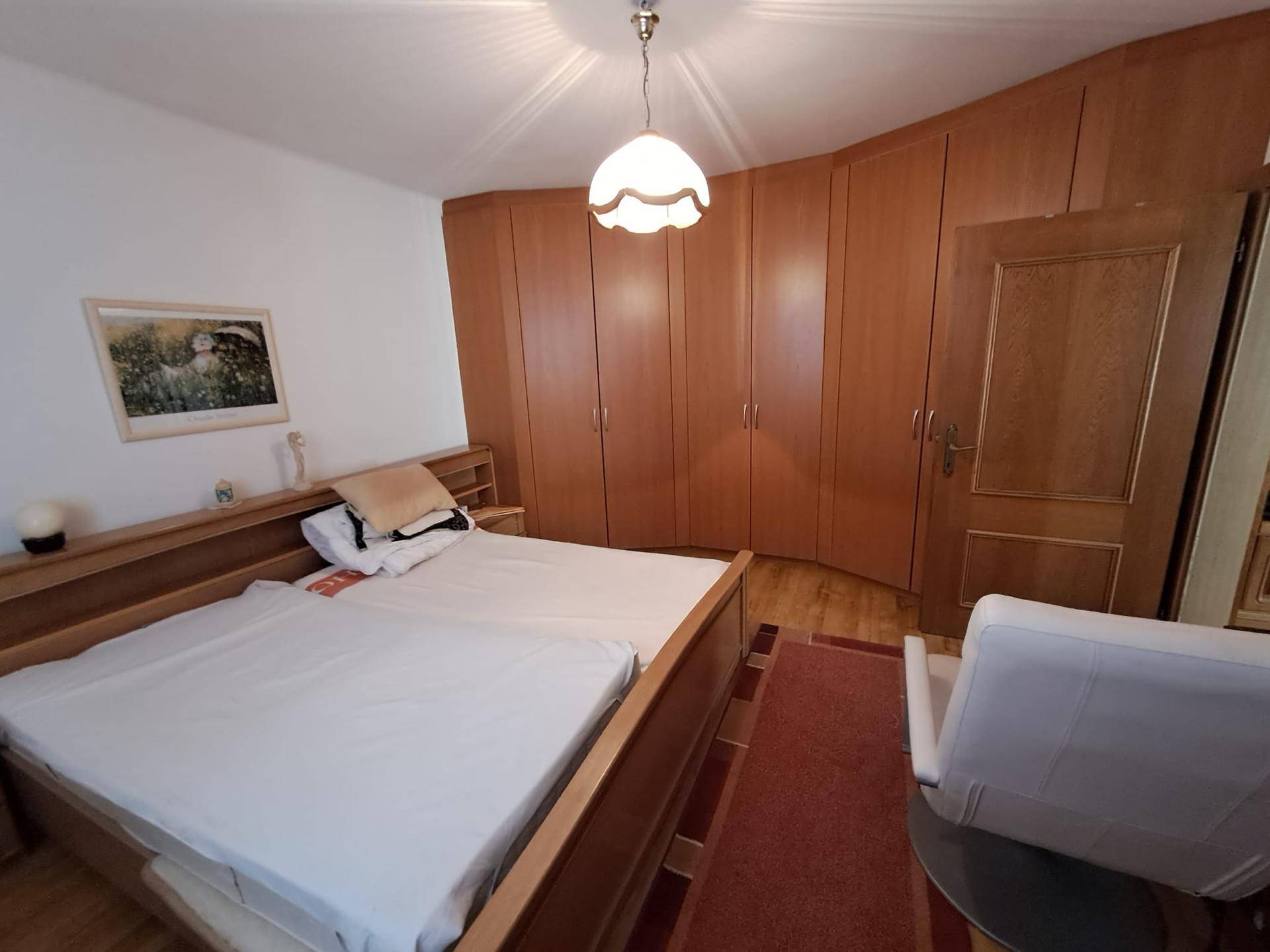 Schlafzimmer mit Doppelbett, Einbauschränken aus Holz und hellem Holzboden.
