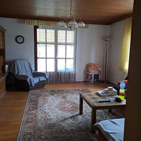 Geräumiges Wohnzimmer mit Holzdecke, Parkettboden, großem Fenster und traditionellen Möbeln.