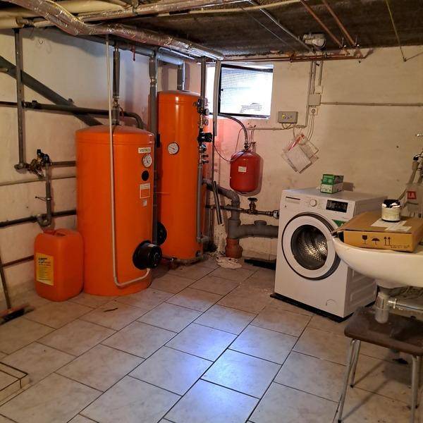 Hauswirtschaftsraum im Keller mit Heizungsanlagen, Waschmaschine, Spülbecken und Fliesenboden.