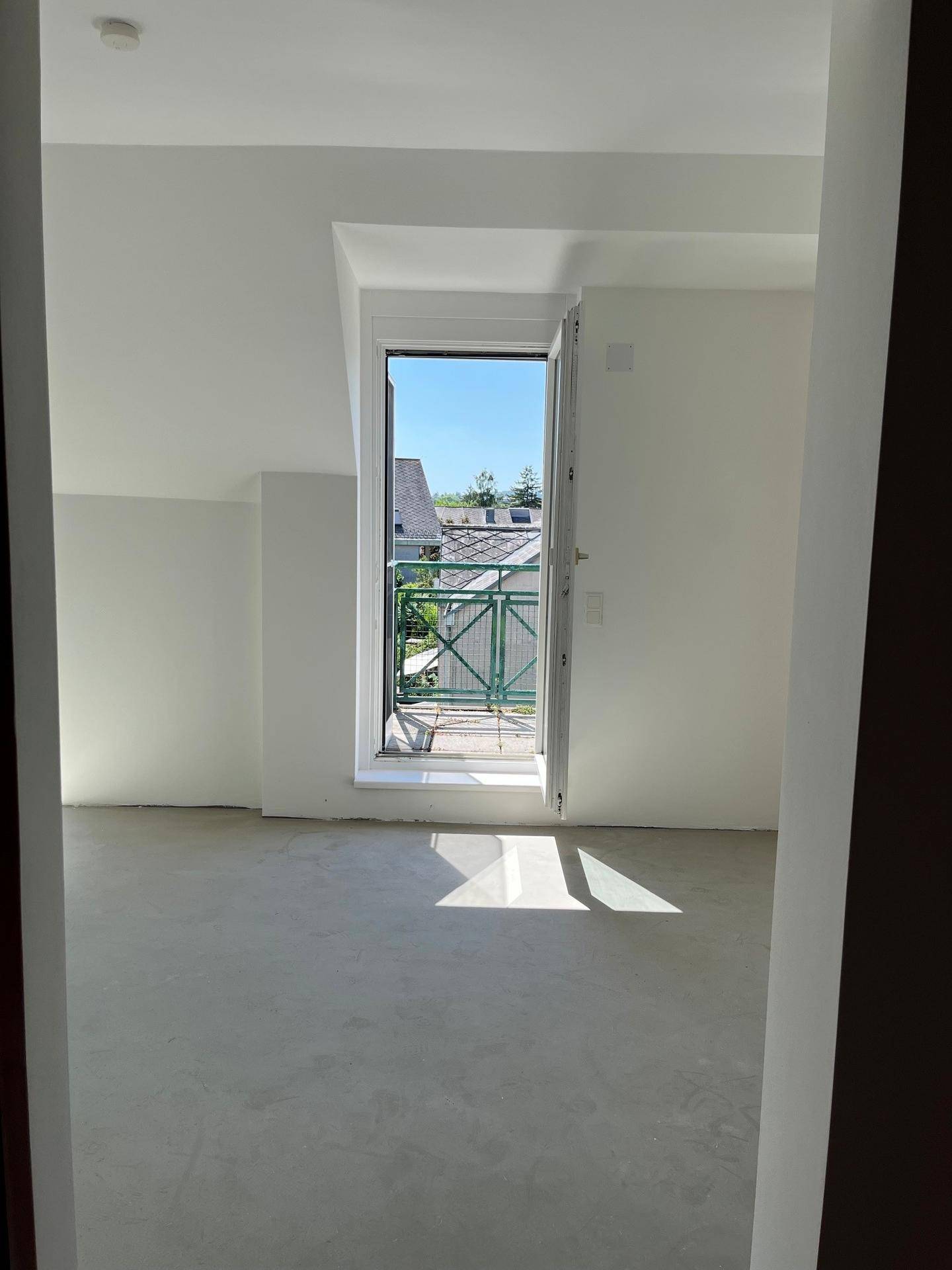 Leerer Raum mit Zugang zu einem Balkon, der viel Tageslicht hereinlässt.