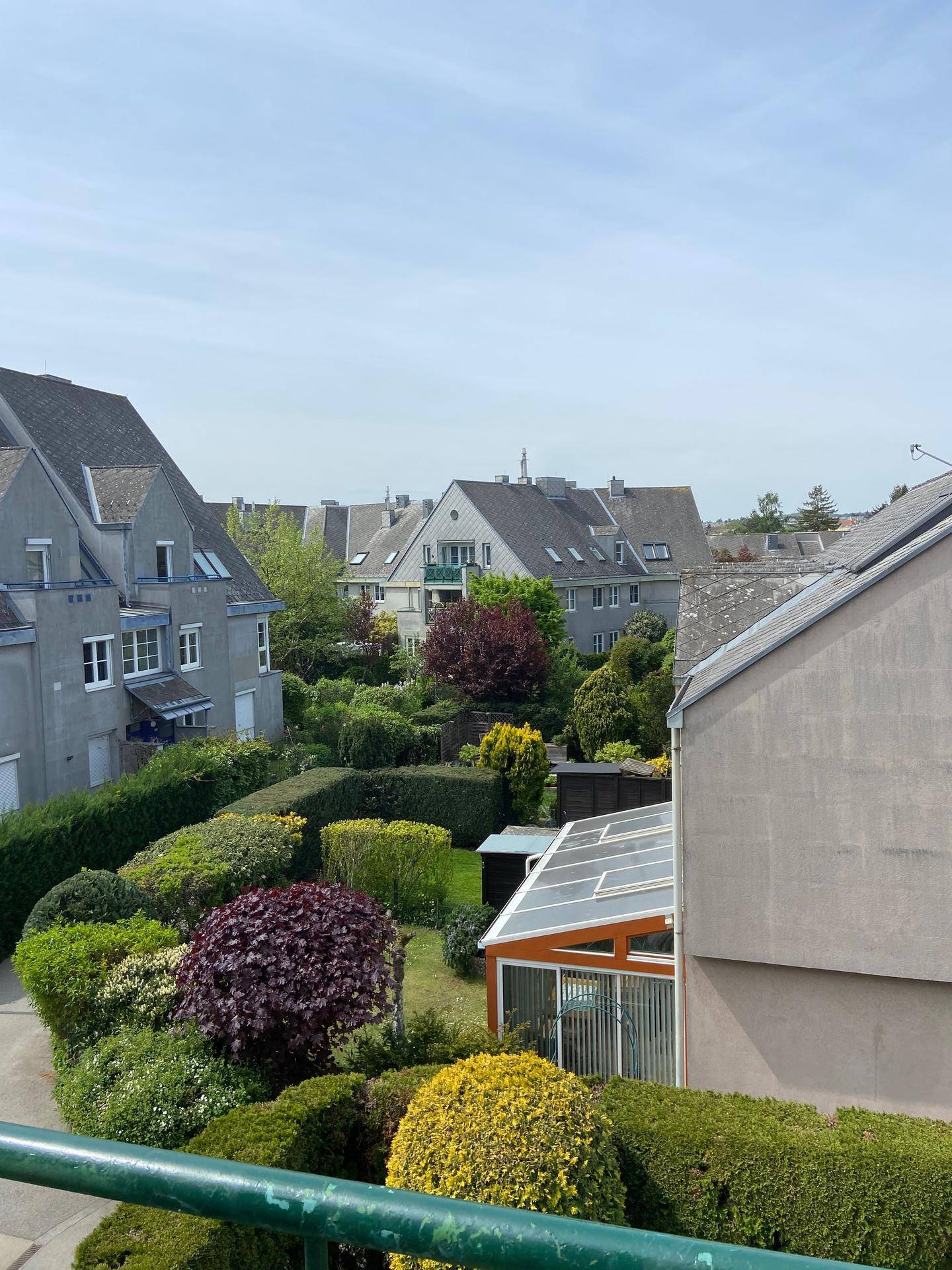 Blick auf eine Wohnsiedlung mit gepflegten Gärten und traditionellen Häusern.