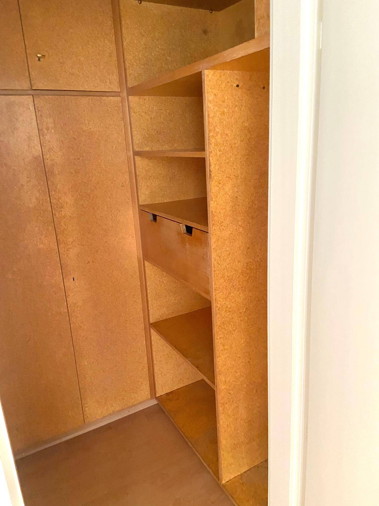 Innenansicht eines Einbauschranks mit Regalen und Schubladen, aus hellem Holz gefertigt.