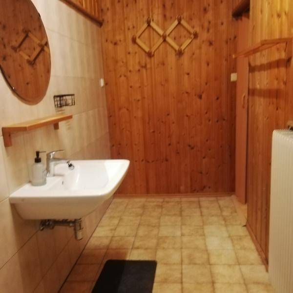 Badezimmer mit Holzvertäfelung, Fliesenboden und einem modernen Waschbecken.