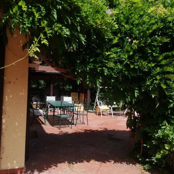 Überdachte Terrasse mit Gartenmöbeln und üppiger Begrünung, ideal für entspannte Stunden im Freien.