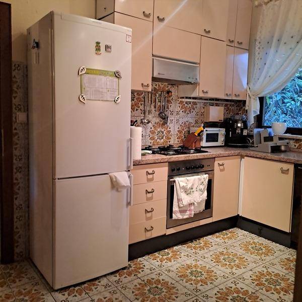 Funktionale Küche mit großem Kühlschrank, Einbauherd und gemustertem Fliesenboden.