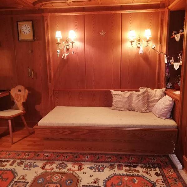 Gemütliches Zimmer mit Holzvertäfelung, integriertem Tagesbett und traditionellem Teppich.
