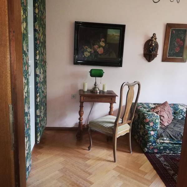 Kleiner Wohnbereich mit Fischgrätparkett, floraler Tapete und klassischem Sofa.