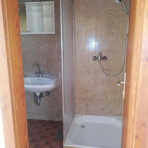 Badezimmer mit beigefarbenen Fliesen, einer Dusche und einem Waschbecken mit Spiegelschrank.