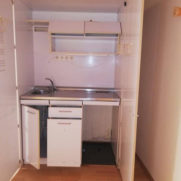 Kompakte Küchenzeile in einem Schrank integriert, mit Spüle und Stauraum.