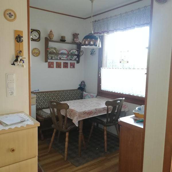 Gemütlicher Essbereich mit Eckbank, Holztisch und Fenster, geschmückt mit dekorativen Tellern.