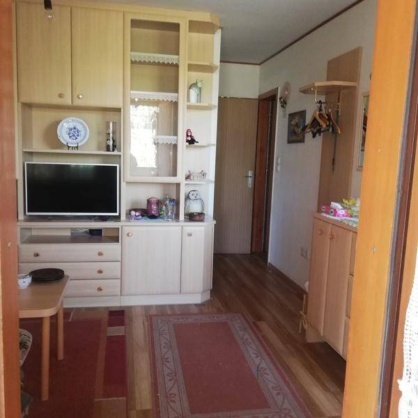 Flur und Wohnbereich mit heller Schrankwand und Garderobe, die zu weiteren Räumen führt.