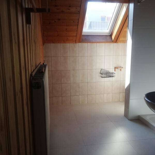 Helles Badezimmer mit Fliesen, Holzverkleidung und einem Dachfenster im oberen Stockwerk.