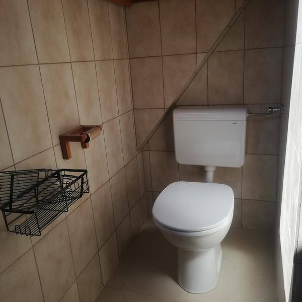 Separate Toilette mit Fliesen an den Wänden und einem einfachen WC-Becken.