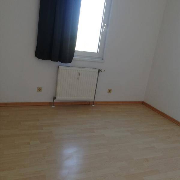 Freundliches Zimmer mit Laminatboden, großem Fenster und Heizkörper, gut belichtet und gepflegt.