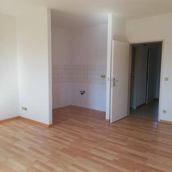 Heller Raum mit Laminatboden und vorbereiteter Küchennische, ideal für eine kleine Einbauküche.
