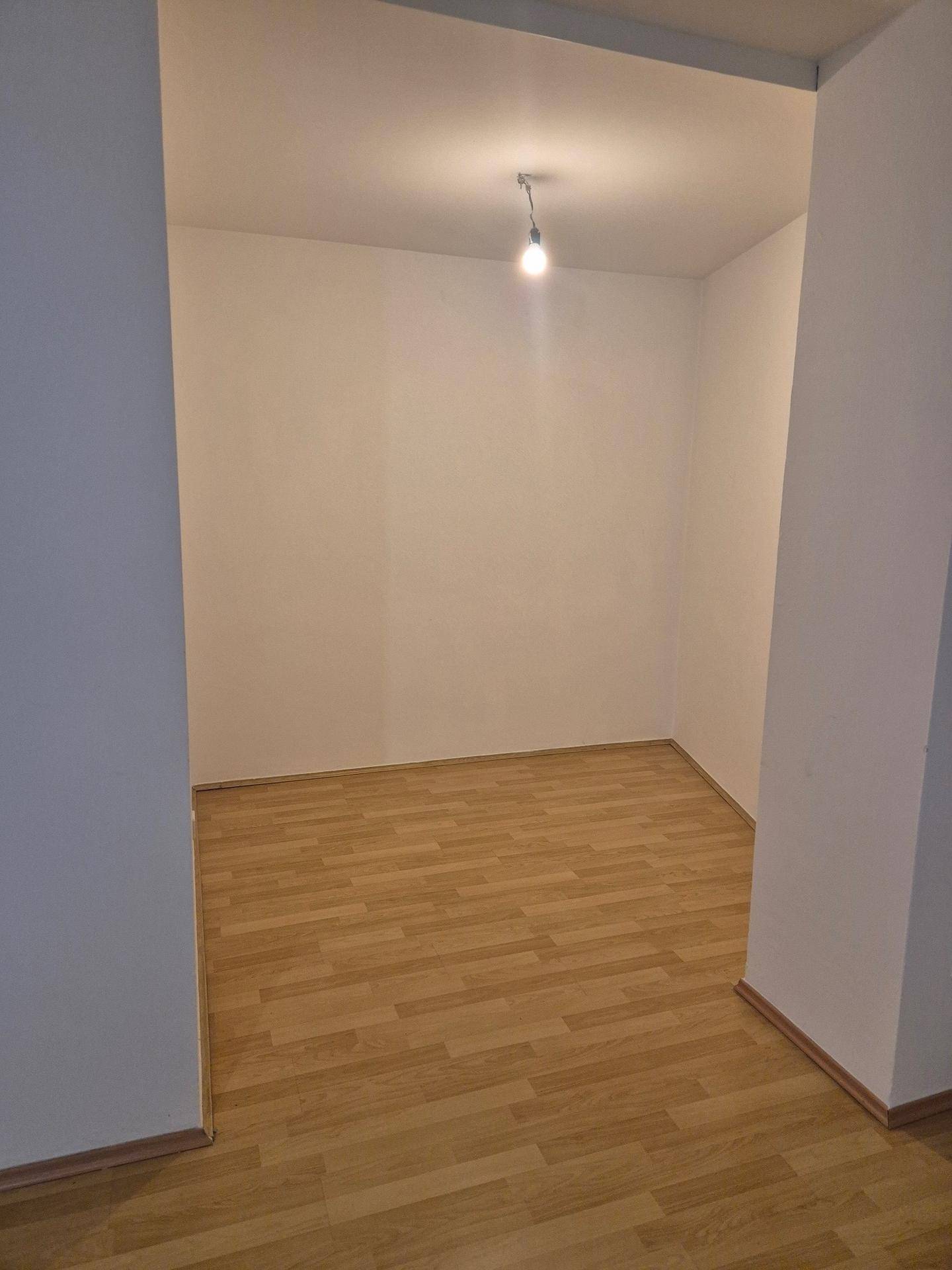 Leerer Raum mit Parkettboden, zugänglich durch einen breiten Durchgang, der eine flexible Nutzung ermöglicht.