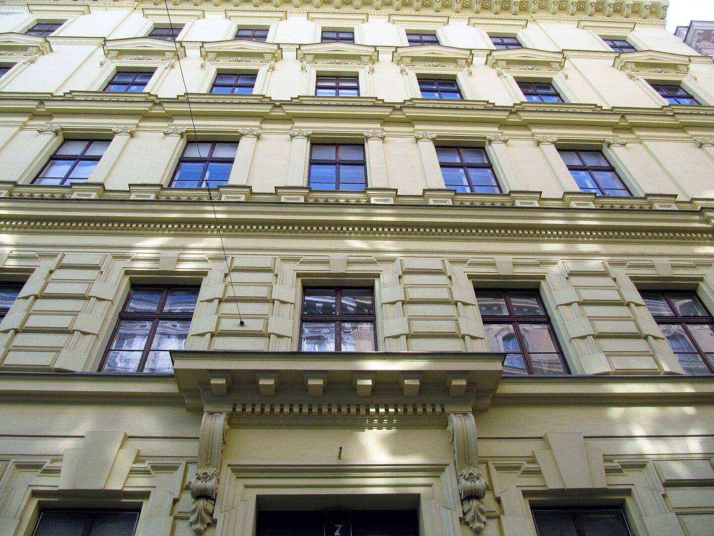 Historische Fassade eines Altbaus mit vielen Fenstern und dekorativen Elementen.