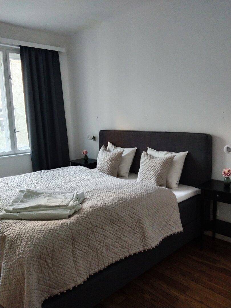 Schlafzimmer mit Doppelbett, Nachttischen und dunklen Vorhängen, bietet eine ruhige Atmosphäre.