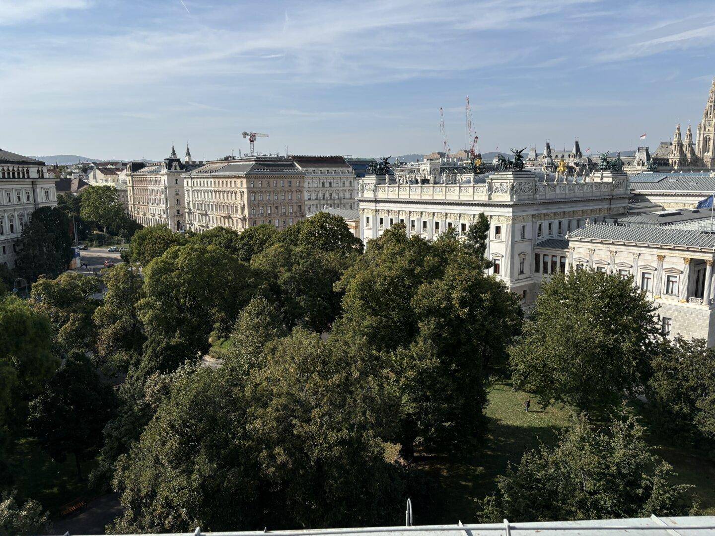 Panoramablick auf die Stadt mit historischen Bauten, üppigem Grün und klarer Himmelsansicht.