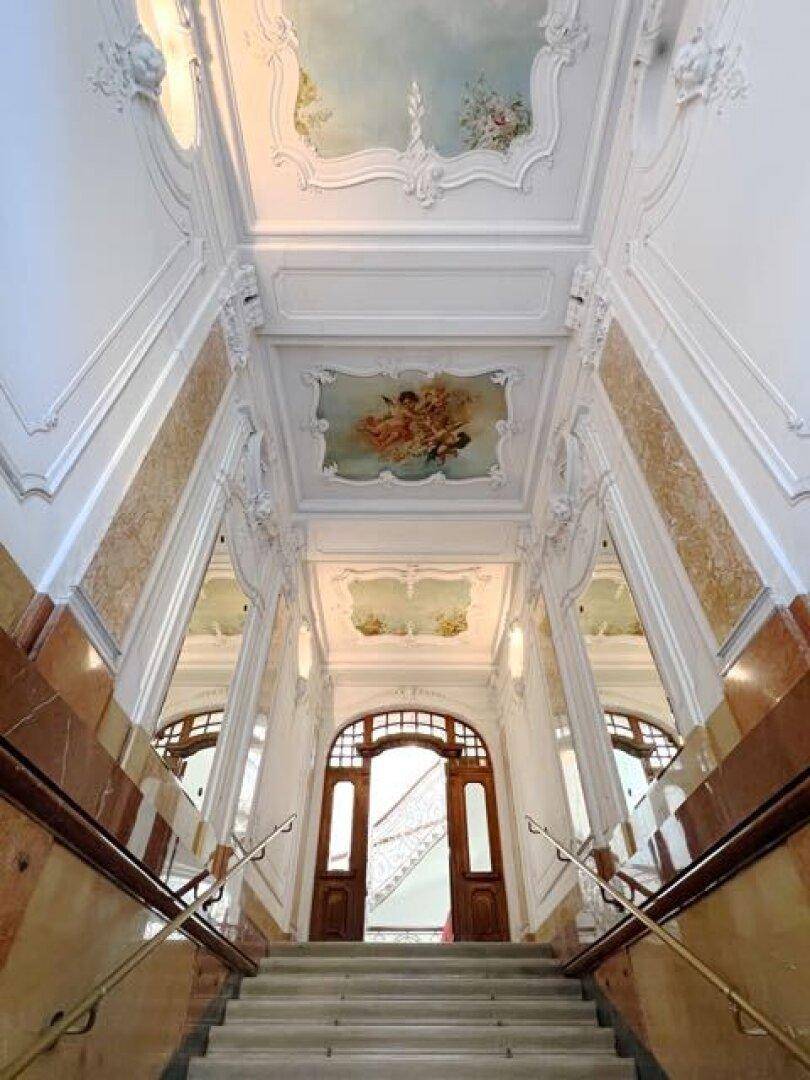 Prunkvolles Treppenhaus mit kunstvollen Stuckdecken, Wandmalereien und Marmorverkleidungen.