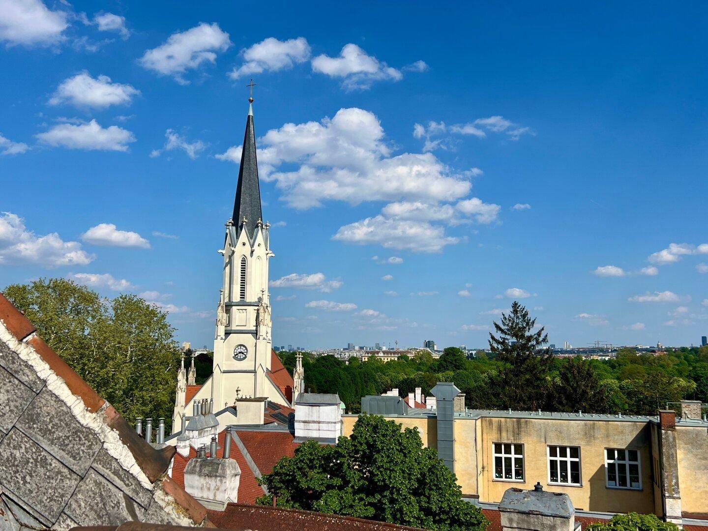 Panoramablick über die Stadt mit einer markanten Kirchturmspitze unter blauem Himmel.