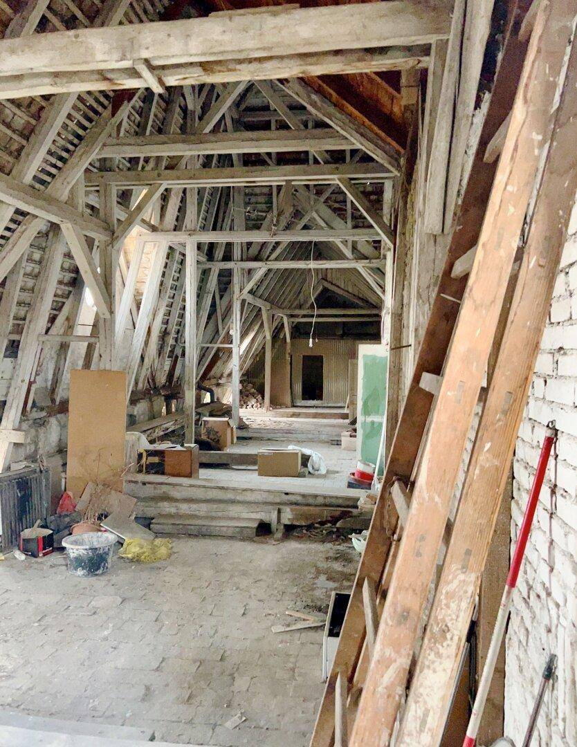 Geräumiger, unausgebauter Dachboden mit Holzkonstruktion und Baumaterialien, bereit für den Ausbau.