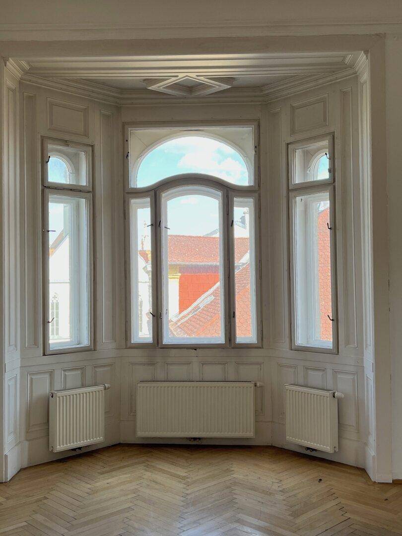 Detailansicht eines Erkerfensters mit Heizkörpern und klassischer Wandverkleidung.